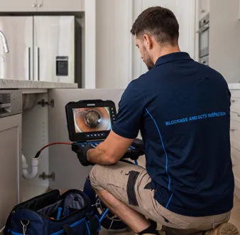 Plumber clearing a blocked toilet in a Enmore bathroom